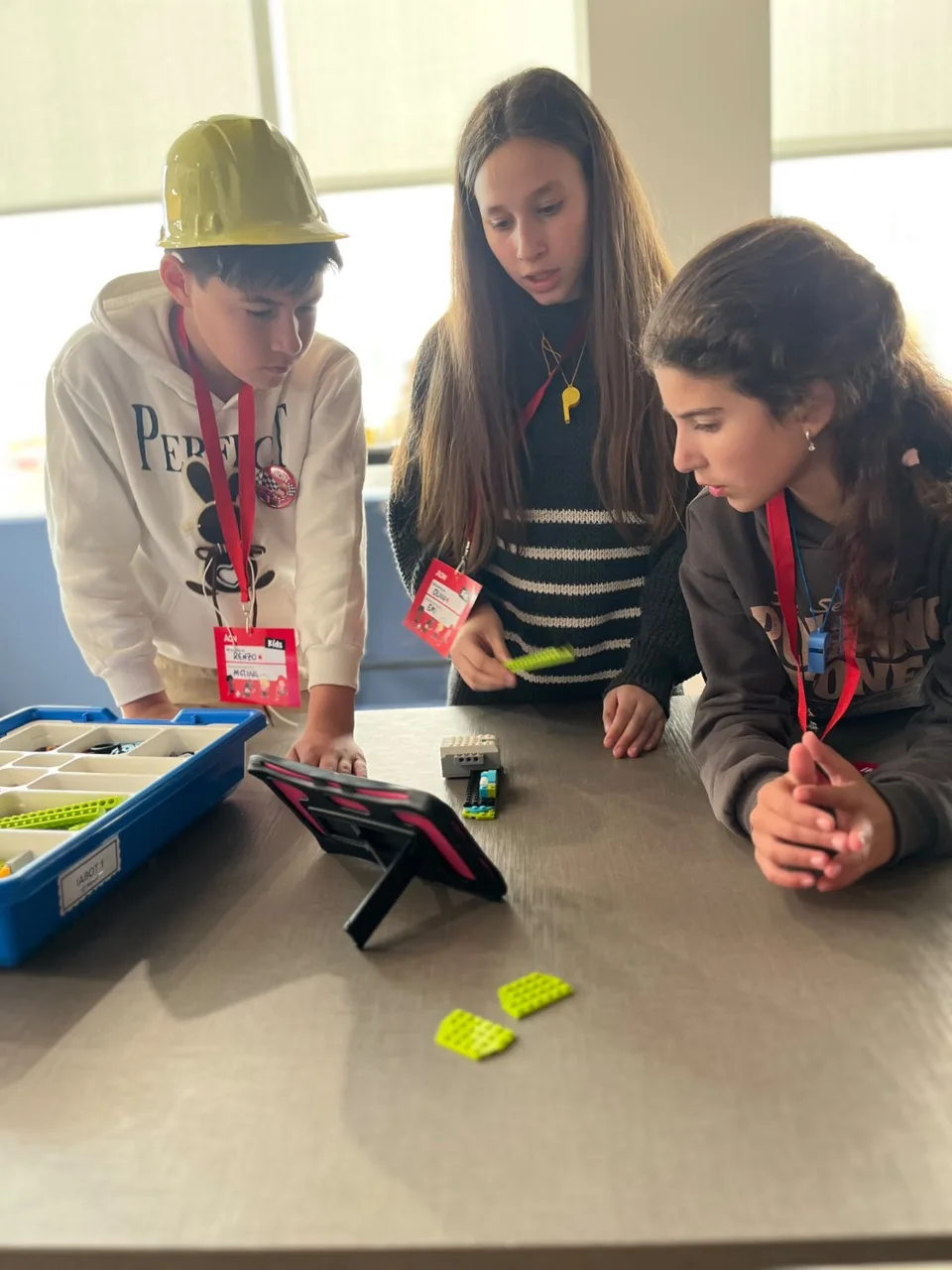 Tres participantes observan su robot junto a una tablet